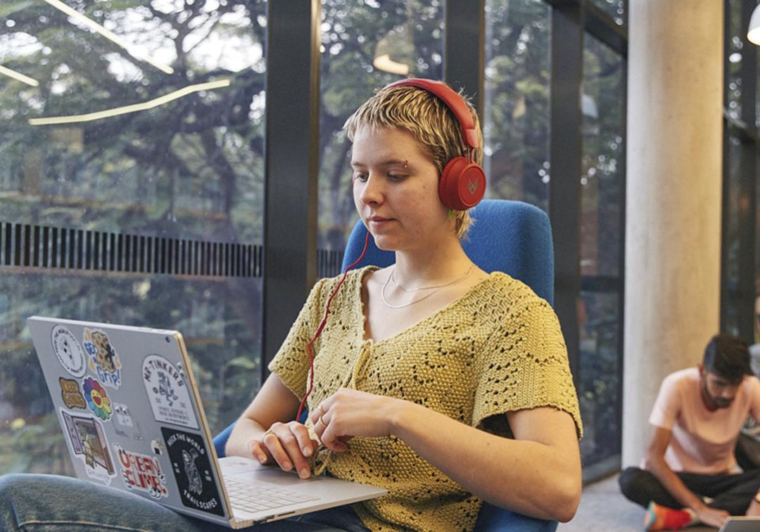 Student with headphones on laptop.